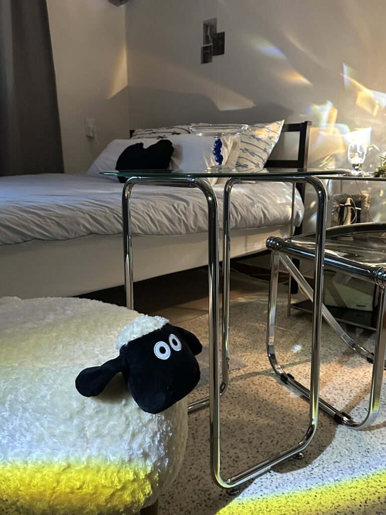 Chrome side tables with glass tops next to fluffy sheep stool in pastel blue ballet core bedroom